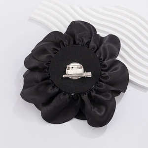 Detailed back view of large black satin flower pin with dual-use metal hair clip and brooch
