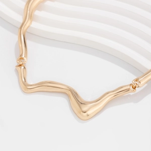 Macro detail of golden liquid metal choker featuring irregular wavy textured design