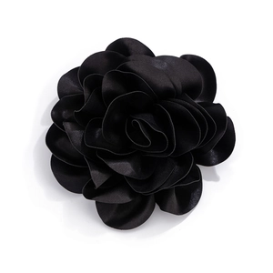 Macro shot of large black satin fabric flower brooch featuring layered rose petal details