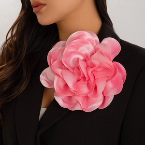 Detail of large pink satin rose brooch pinned on a black blazer for a layered floral look