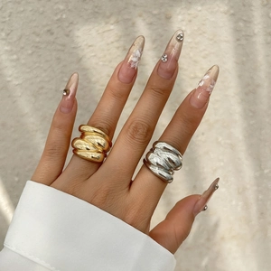 Detail of wavy textured gold and silver metal rings on a manicured hand