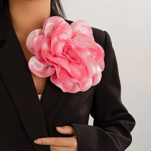 Oversized pink satin flower brooch and hair clip on black suit for a chic look
