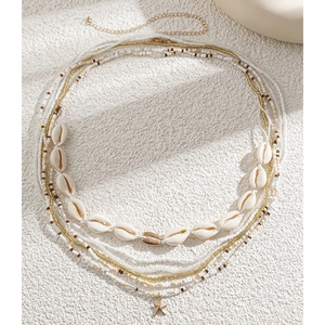 Detailed macro of bohemian shell beads and golden starfish charms on a multi-layer chain