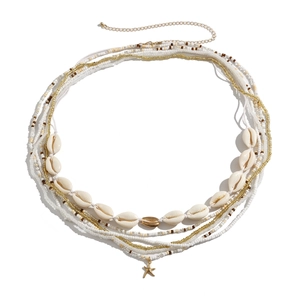 Detail van een bohemian gelaagde tailleketting met kralen en gouden zeester hanger