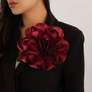 Close-up of oversized burgundy satin rose brooch pinned on a black suit blazer