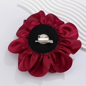 Detailed view of burgundy satin flower brooch with metal pin and duckbill clip on back