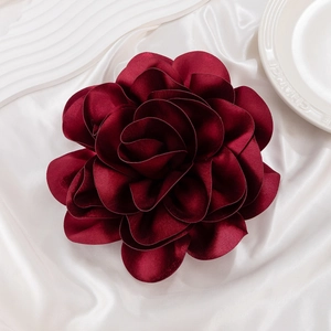 Macro shot of large wine red satin flower brooch with glossy layered silk petals