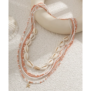 Detail of layered waist chain with coral beads, natural shells and a gold starfish charm