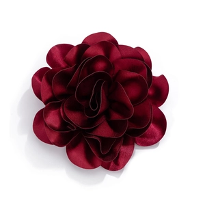 Macro detail of wine red satin rose brooch showing layered silk fabric petals
