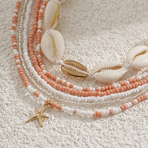 Detail van koraal en witte kralen met schelpen en gouden zeester hanger sieraad