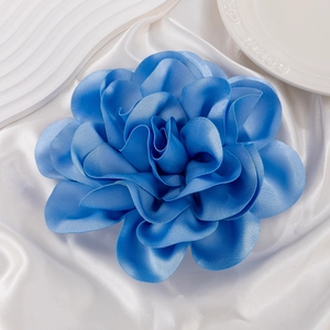 Close-up of a large blue satin fabric rose brooch with detailed silky petal textures