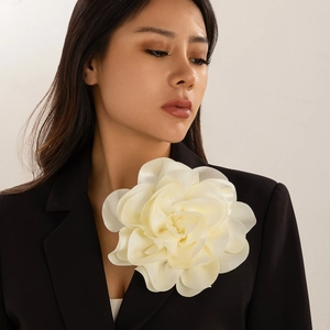Detailed view of large cream satin fabric flower brooch pinned on a black blazer