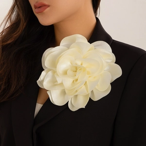 Macro detail of large cream satin fabric flower brooch on black blazer jacket