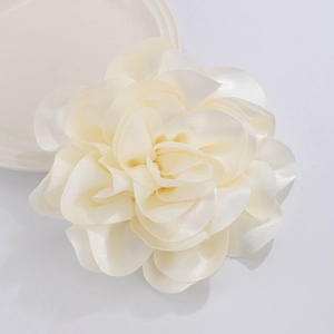Detail of a large cream satin fabric flower brooch with layered petals and soft luster