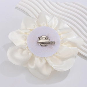 Detail of white satin rose brooch with dual pin and duckbill clip on elegant stone base