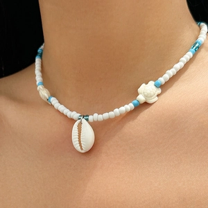 Detail of beach necklace featuring small blue beads with a white shell and sea turtles