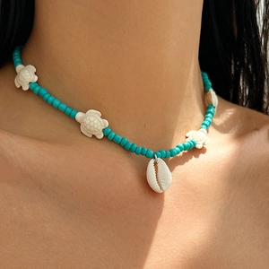 Detail of turquoise beaded necklace with sea turtle charms and white cowrie shell pendant