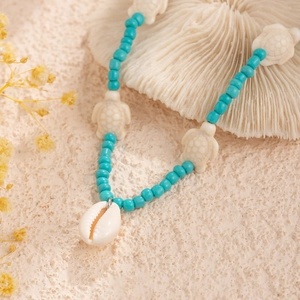 Close-up of blue ocean-style beads with small turtle accents and a natural shell pendant