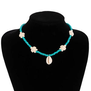 Detail of beach necklace featuring turquoise beads, faux bone turtles and a cowrie shell