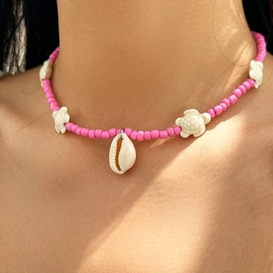 Detail of pink beaded necklace with white sea turtles and shell pendant on model