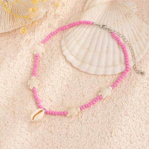 Detail of beach necklace with pink beads, sea shell charm, and turtle pendant detail