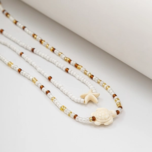 Détail d'une chaîne de corps bohème en perles avec breloques d'étoile de mer et tortue