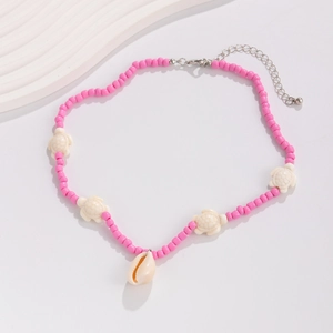 Detail of pink beaded necklace with white turtle charms and natural shell pendant