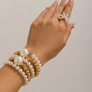 Detalle del conjunto de pulseras de perlas multicapa con cuentas de oro y anillo moño