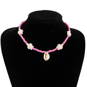 Detail of pink beaded necklace with small white turtles and a natural conch shell pendant