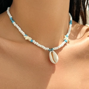 Detail shot of a bohemian beaded necklace featuring a white shell and starfish charms