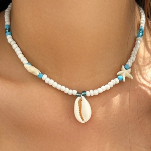 Detail of beaded ocean necklace with shell and starfish charms worn by a model