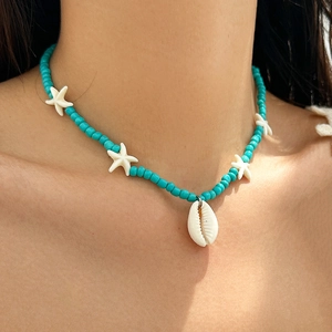 Detail of blue bead necklace with white starfish charms and shell pendant on neck