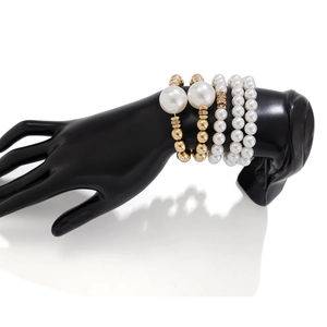 Elegante conjunto de cuatro pulseras de perlas blancas y cuentas doradas en soporte negro