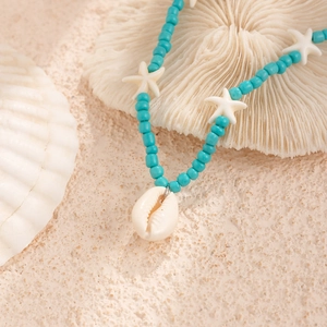 Close-up of beach necklace featuring turquoise beads, white starfish and shell pendants