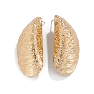 Detalle de pendientes metálicos dorados con textura cepillada y diseño de concha marina
