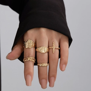 Detail of 5-piece gold lava texture rings set worn on fingers with irregular metal patterns