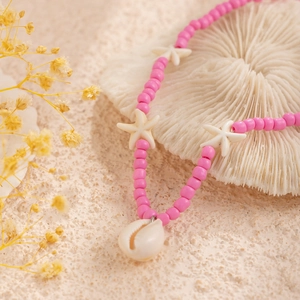 Detail of pink beaded necklace with white star spacers and a natural seashell pendant
