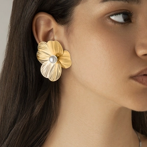 Detail of ginkgo flower earring with brushed gold metal finish and white faux pearl center