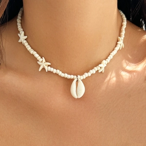 Detail of beaded starfish necklace with shell pendant worn on neck in natural sunlight