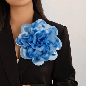 Exaggerated royal blue satin rose brooch pinned on a black suit blazer for women