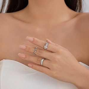 Detailed view of silver lava texture rings and irregular smooth metallic bands on hand