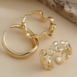 Macro detail of three gold lava style geometric rings set on a natural stone base