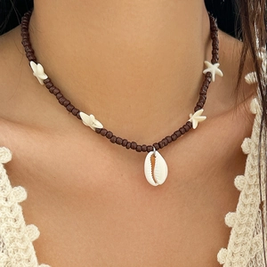 Detail view of beach beads necklace with white starfish and shell charms on lace collar