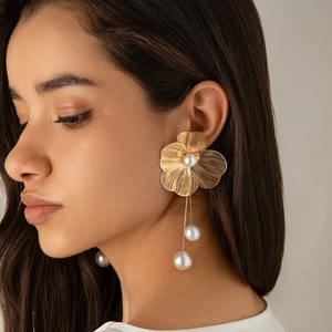 Detail of gold floral dangle earring with radial textures and lustrous pearl fringe