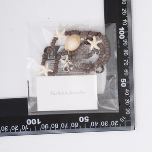 Detail of beach ocean necklace with sea stars and shells measured on a scale card