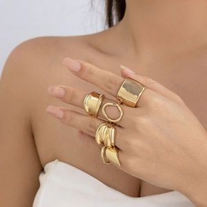 Close-up of five-piece gold metal ring set featuring irregular geometric lava textures
