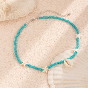 Blue beaded starfish necklace with natural shell pendant on a beach vacation background