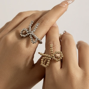 Close-up of golden and silver beaded bow rings worn on fingers showing adjustable open design