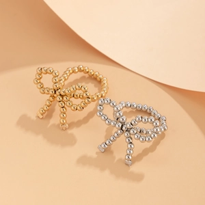 Detail showing gold and silver metallic beaded bow rings on a textured backdrop