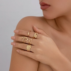 Close-up of golden irregular lava texture rings set worn by a model on hands